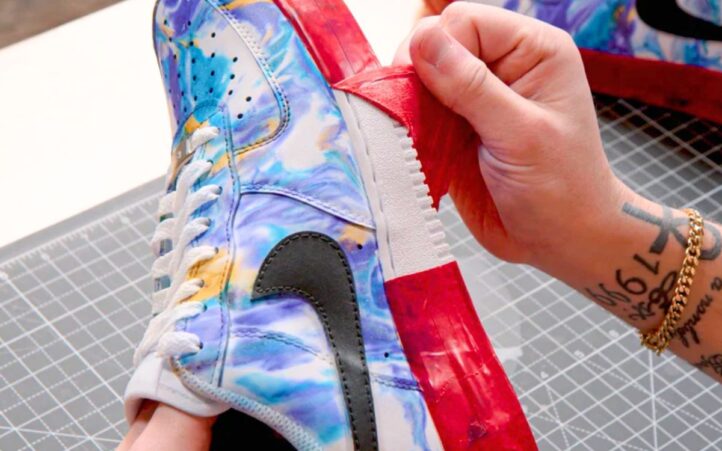 Peeling red masking tape from a customized Nike sneaker